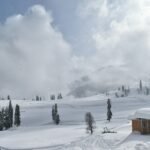 a snow covered mountain with a small cabin in the foreground